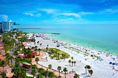 An overhead shot of a crowded white sand beach on the edge of the city during the day.