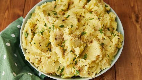 A bowl of mashed potatoes with skins and rosemary mixed in.