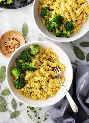 A bowl of yellow rotini pasta with broccoli.