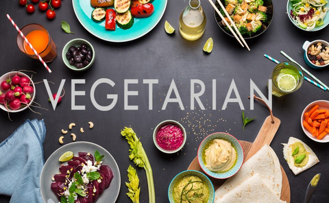 White text reading "Vegetarian" over an assortment of frutis, vegetables, and other food items.