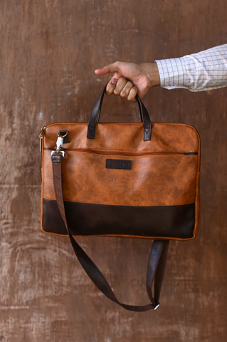 A brown leather work bag on a brown painted background.