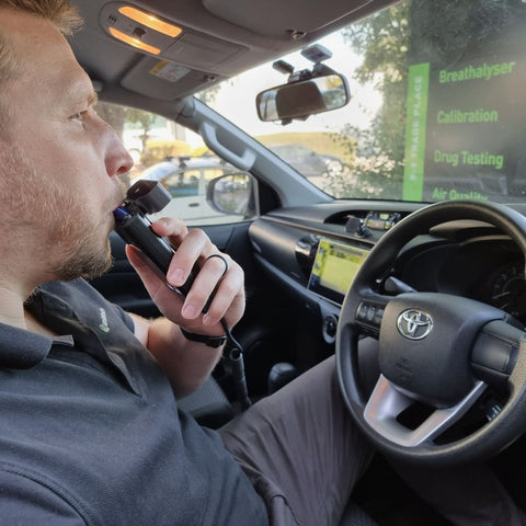 Man blowing into alcohol interlock car breathalyser