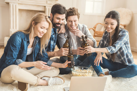 Two young couples watching movie on laptop while drinking beer and eating popcorn