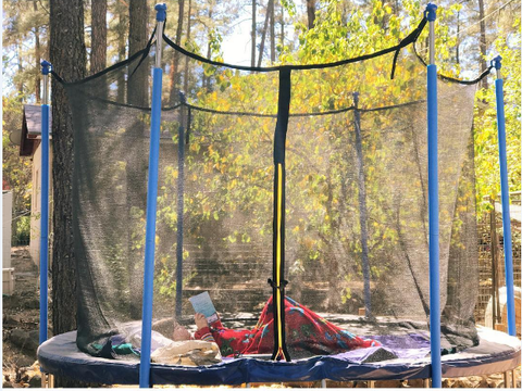 A kid enjoy reading on a Zupapa 15 ft. trampoline
