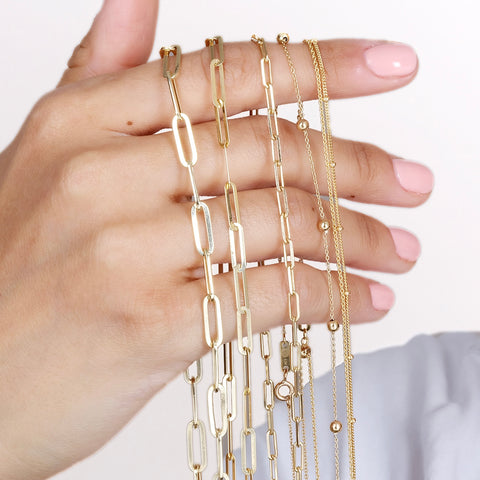 Paper clip, Rope, Cuban, Beaded chains in solid gold all shown on a model's hands