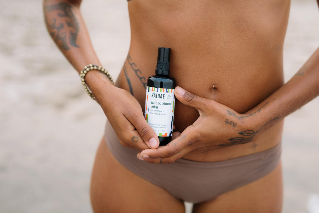 woman on beach holding kaibae prebiotic microbiome mist skincare facial spray with postbiotics