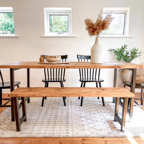 Reclaimed wooden industrial dining table with black chairs and bench