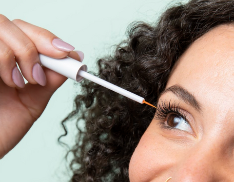 Woman applying lash serum to her lashes