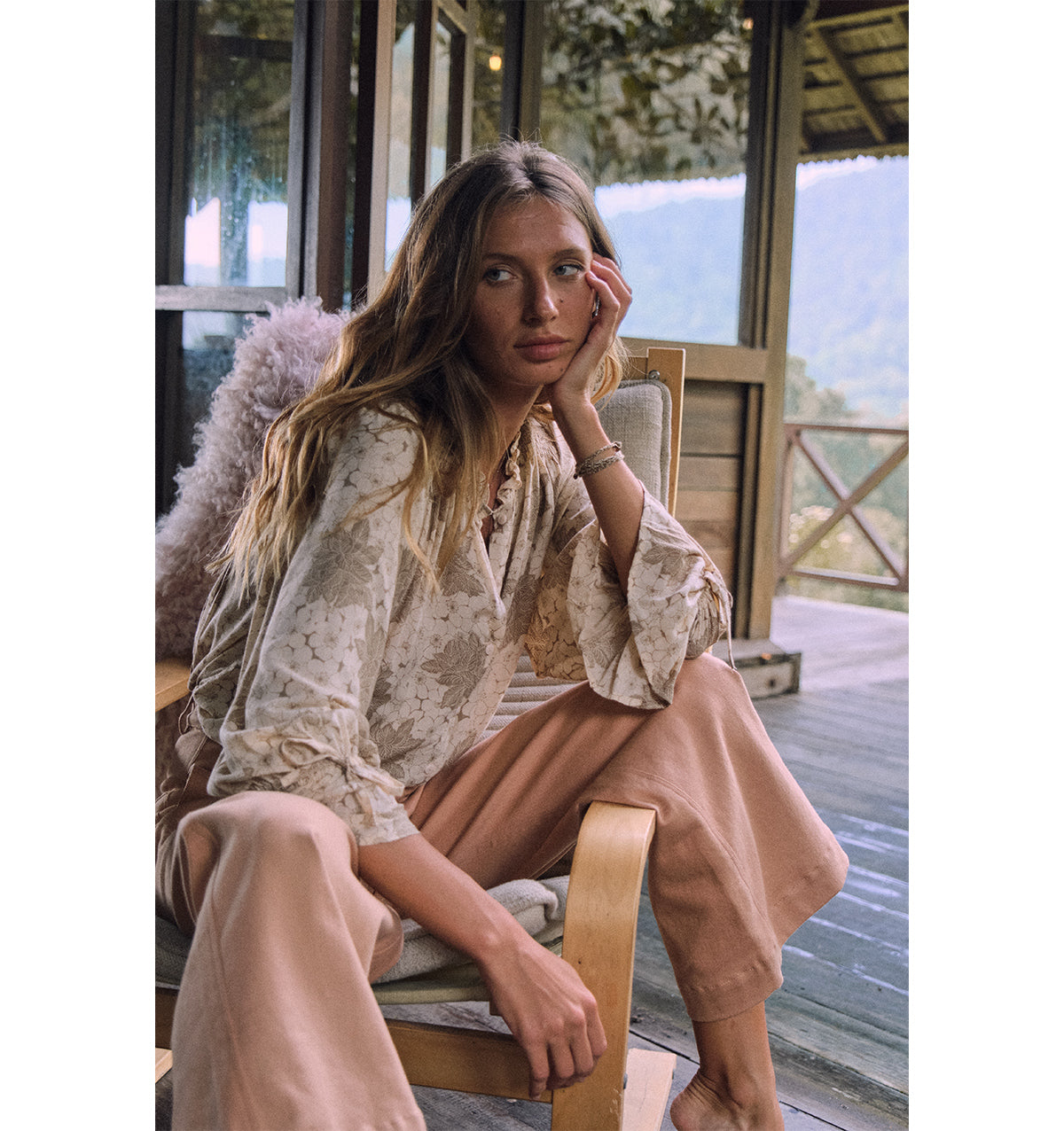 A woman wearing mohave blouse in floral khaki and brown pants