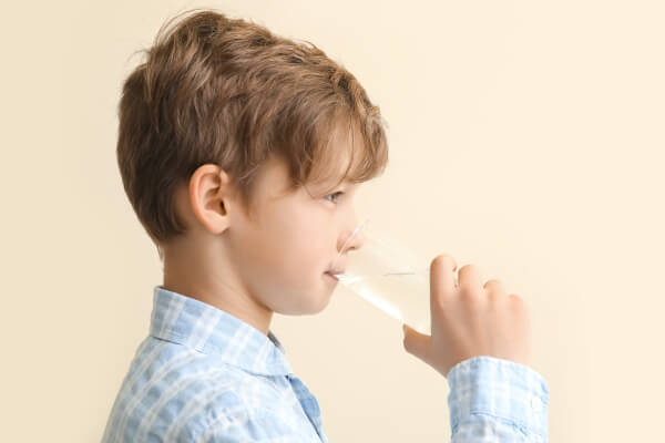 young boy drinking water from a glass