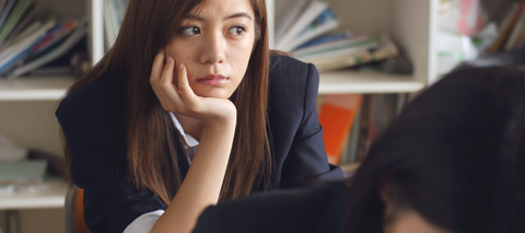 unfocused woman resting chin in hand and looking distractedly at corner of room