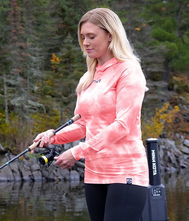 Image of a woman fishing, wearing FXR's Attach UPF Pullover Hoodie.