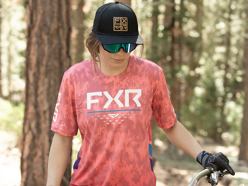 Image of guy in FXR's new Proflex UPF Shirt in HiVis fade/blue fade colorway, preparing the trail for mountain bike tricks