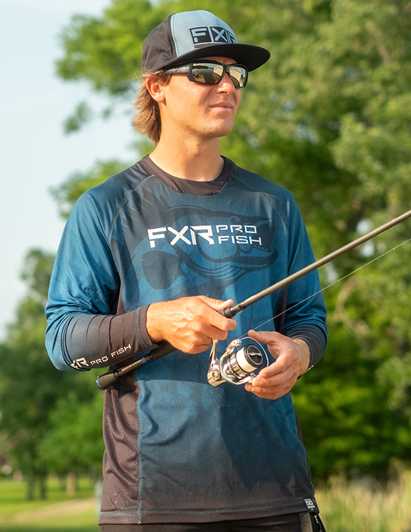 Image of a man out fishing in his FXR’s slate blue camo Derby UPF pullover hoodie.