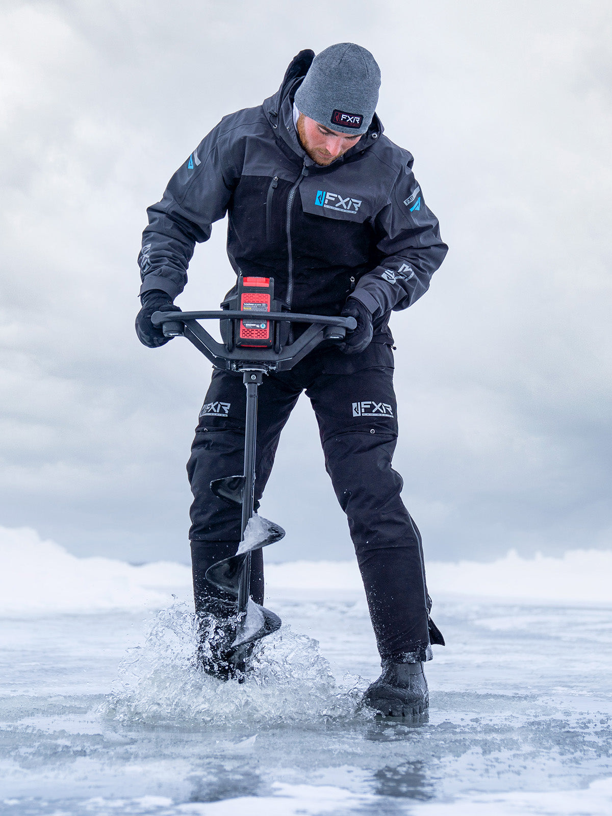 Action image of a guy ice fishing and sporting a gear from FXR's Pro Ice Series collection