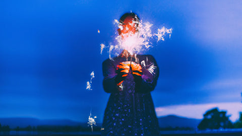 Woman holds sparkler in front of her. 