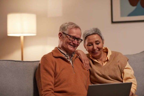 Happy elderly couple, looking at laptop