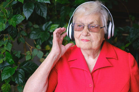 Elderly lady in a red top listening with headphones