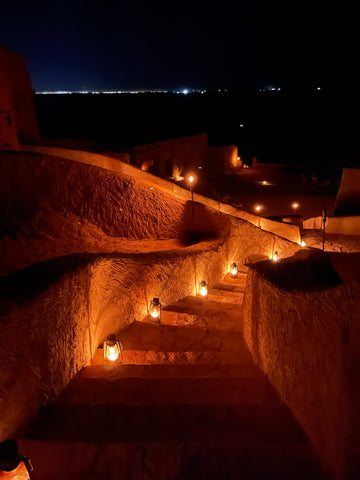 Una imagen de una escalera exterior iluminada de color beige por la noche.