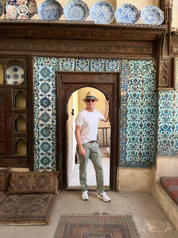 Une photo d’un homme debout devant une porte carrelée de bleu.