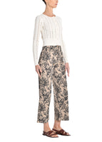 A side image of a model wearing khaki floral pants. 