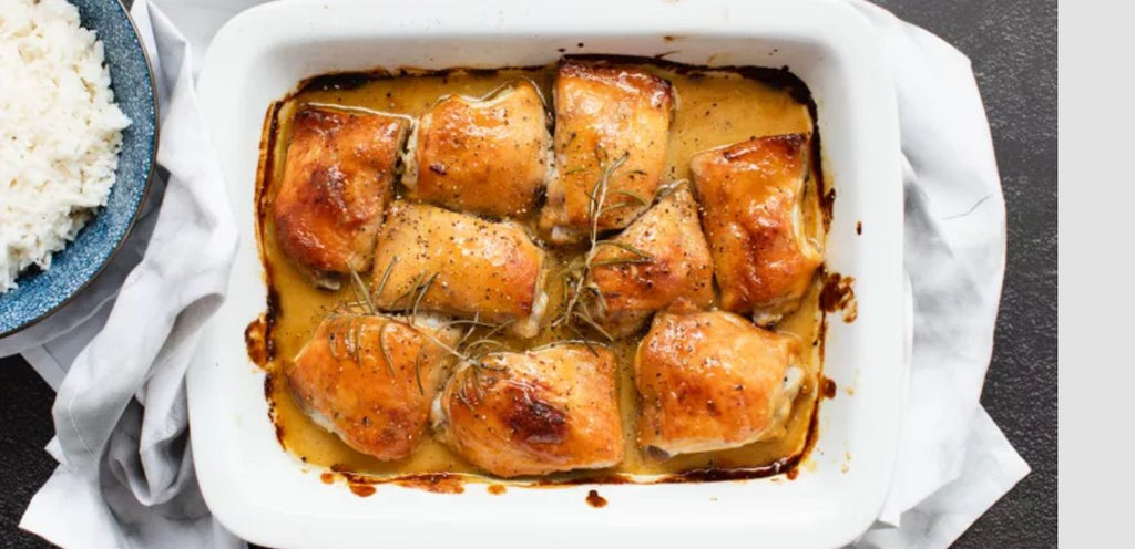 A baking dish with baked honey mustard chicken is featured, with a garnish of thyme. A bowl of rice sits to the side.