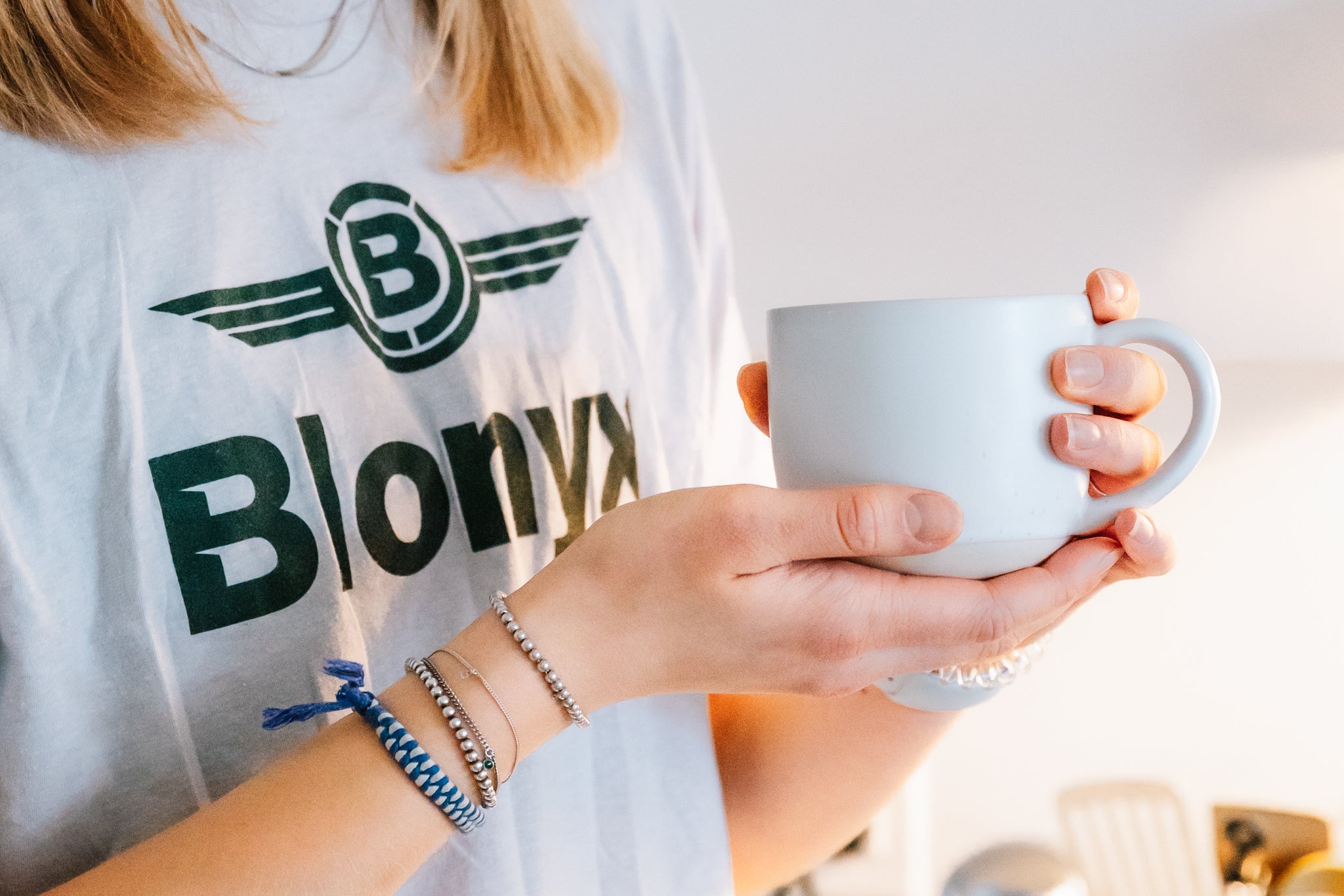 Woman holding a mug of coffee wearing a Blonyx shirt