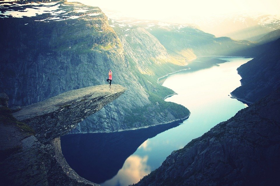 Woman doing yoga on a cliff.