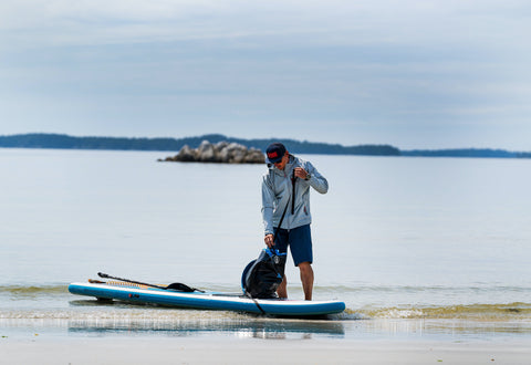 norm hann standing beside a sup on the shore