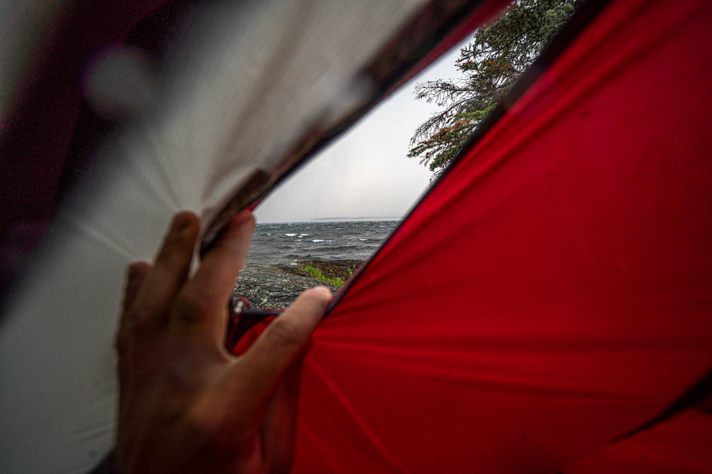 Peeking out of a tent to a wavy lake