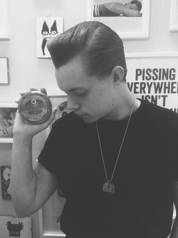 Holding up the can of pomade in black and white
