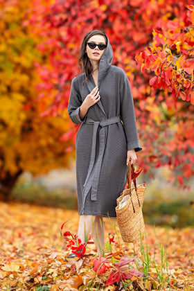 Elegant woman draped in a SEYANTE Turkish cotton bathrobe admiring the autumn leaves