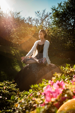 woman meditating outside in a meadow