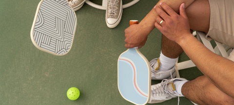 Pickeball paddles & outdoor ball on a pickleball court.