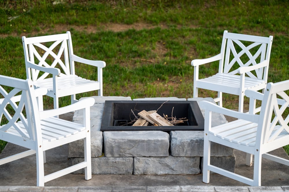 White spray-painted wooden chairs were placed around the fire pit