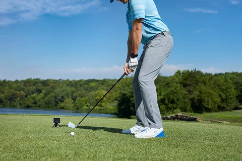 A golfer at the range getting ready to swing using the Garmin Approach R10