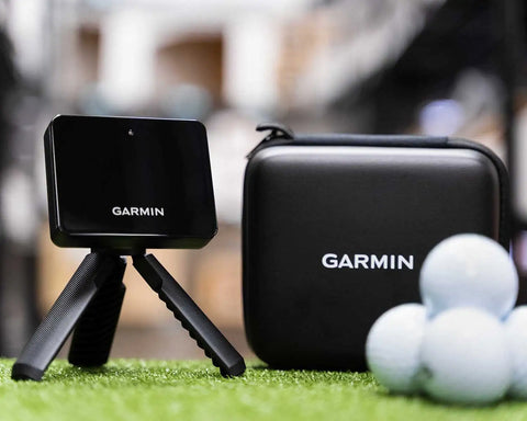 The Garmin R10 next to it's case with a stack of golf balls