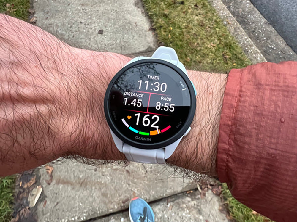 The Garmin Forerunner 165 basic running GPS watch on Chris's wrist showing time, pace, distance and heart rate