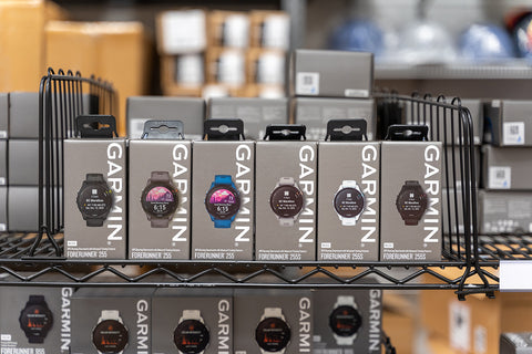Several Garmin Forerunner 255 running watches in product boxes on a shelf in the PlayBetter warehouse