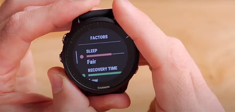 Two hands holding a black Forerunner 955 with sleep and recovery time metrics on the display