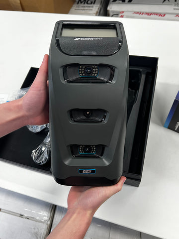 The Foresight Sports GC3 launch monitor being held in the hands of a PlayBetter employee over its packaging above a table