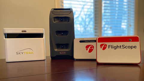 The Skytrak+, Bushnell Launch Pro, FlightScope Mevo+ Limited Edition and Mevo+ units standing upright on a tabletop