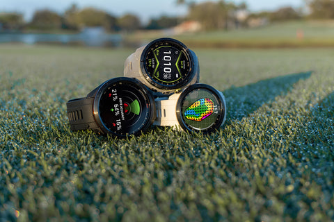 Three Garmin golf watches stacked in a pyramid on a golf course
