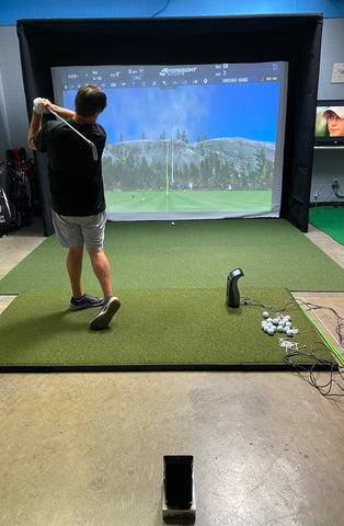 Reviewer Marc swinging in a golf simulator using the Foresight GC3 next to him and Swing Caddie SC4 behind him