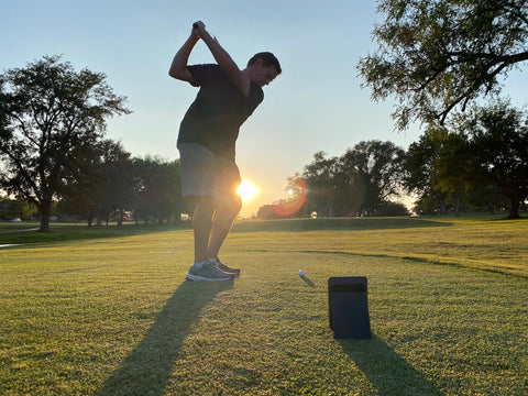 Reviewer Marc swinging the golf range with a sunset in the background and the Swing Caddis SC4 in the foreground