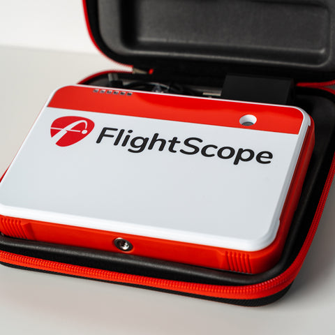 The FlightScope Mevo+ golf launch monitor sitting flat in its case.