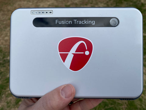 The FlightScope Mevo+ Limited Edition launch monitor held in Marc's hand above grass