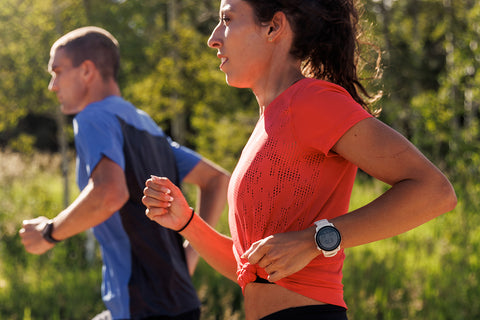 A male and female runner pictured from the waist up running outdoors with Coros Pace 3 watches on their wrists