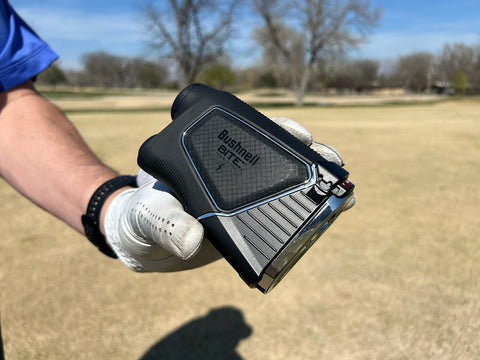 The Pro X3+ rangefinder held with the Bite magnetic mount side facing out in Marc's hand with a white golf glove on it