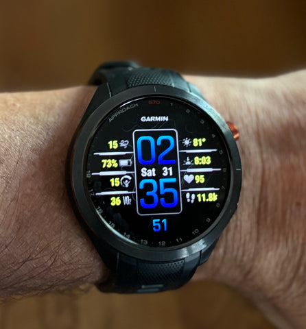 Black Garmin Approach S70 golf watch with lit up Amoled display on golf reviewer Marc's wrist indoors